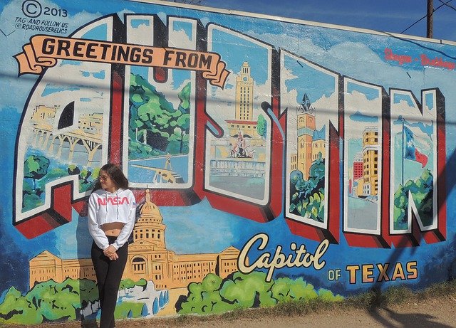 Girl standing in front of Greetings from Austin mural