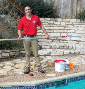 Matt Austin Texas Pool Scouts Owner standing with a pool net in front of a pool