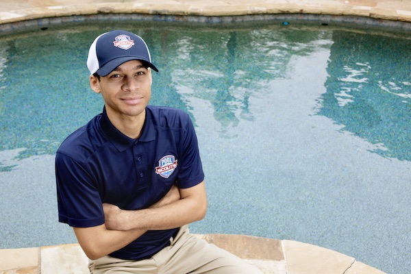 Pool Scouts of Chandler pool technician smiling next to a clean pool he serviced