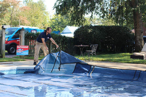 Pool technician putting pool cover on a swimming pool