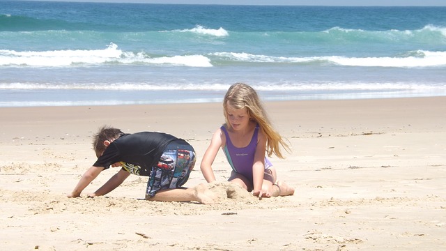 Little boy and girl playing in sand at beach