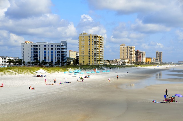 View of Jacksonville Beach on a sunny day, including hotels and beach visitors laying out and walking