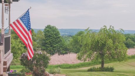 Flag hanging from front porch of a home to support Veteran's Day