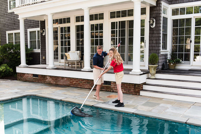 Woman and man cleaning pool