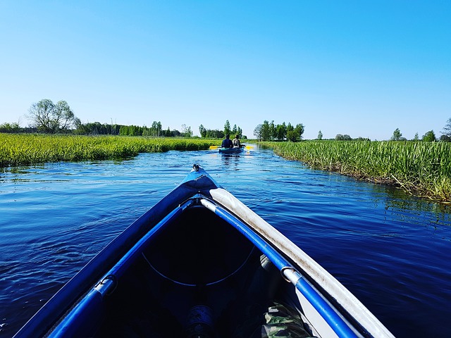 Front of a kayak on a river with another kayak off in the distance