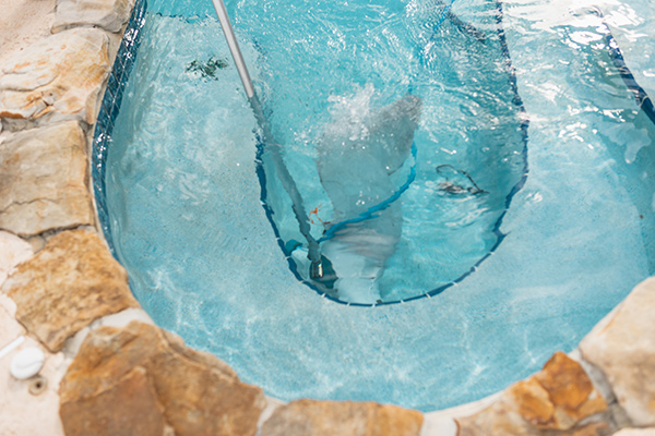 Swimming pool being cleaned with a pool net