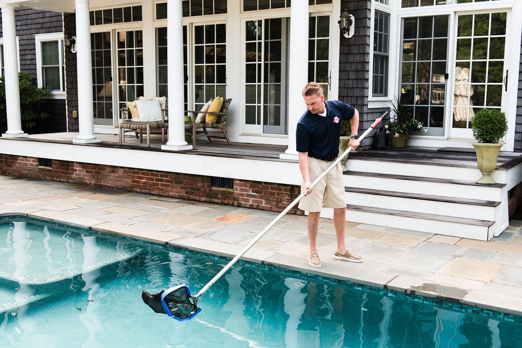 Pool technician skimming leaves out of pool