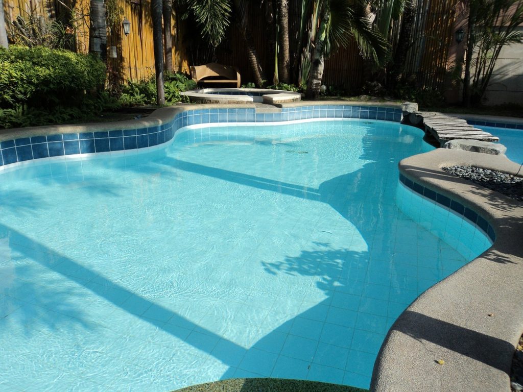 Swimming pool in backyard with fence around it