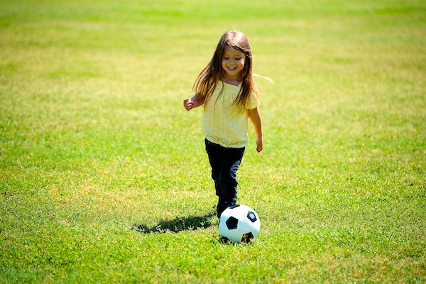 Little girl kicking a soccer ball on a soccer field
