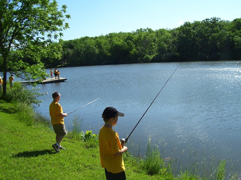 Two boys fishing along a lake