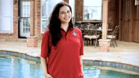 Pool Scouts technician in front of a clean swimming pool to highlight the benefits of using pool service