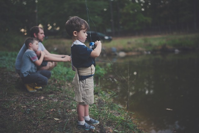 Little boy fishing with his family at a river bank