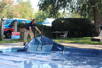 Pool technician putting pool cover on pool as part of closing service