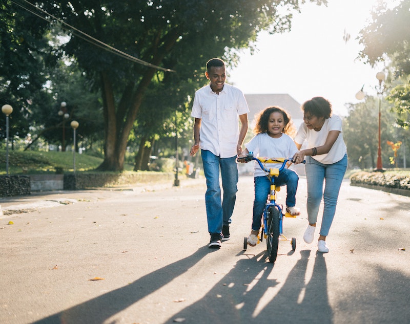 Family teaching child to ride a bike in Texas neighborhood