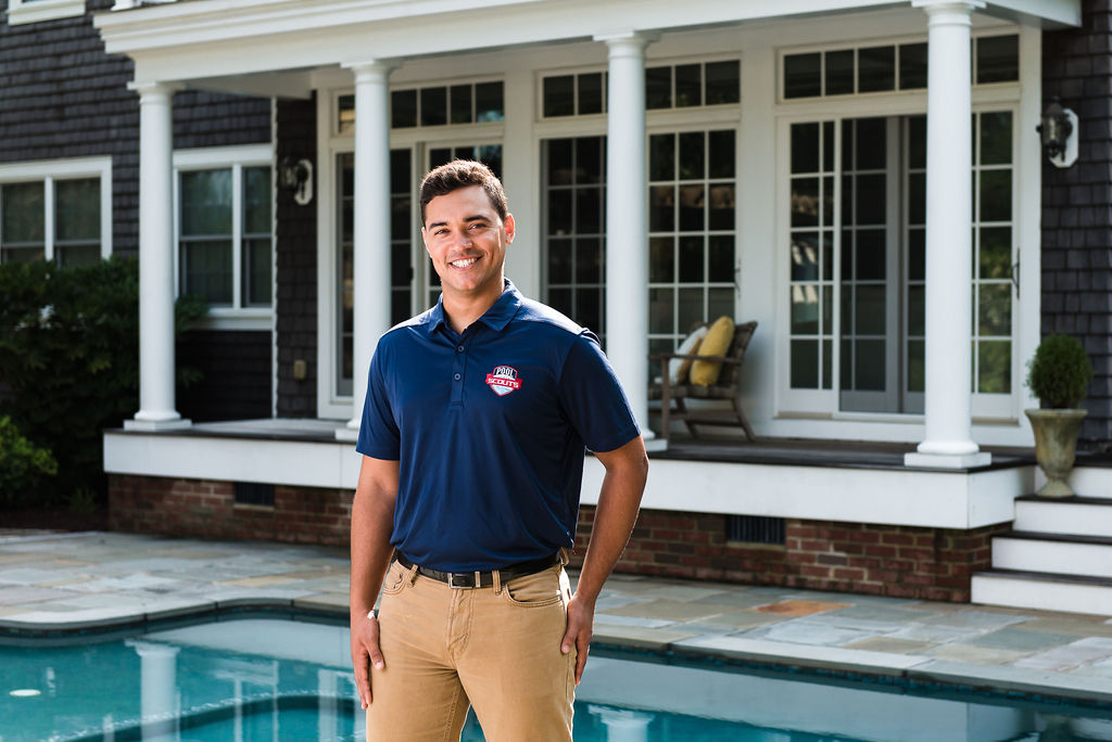 Pool technician standing in front of clean swimming pool