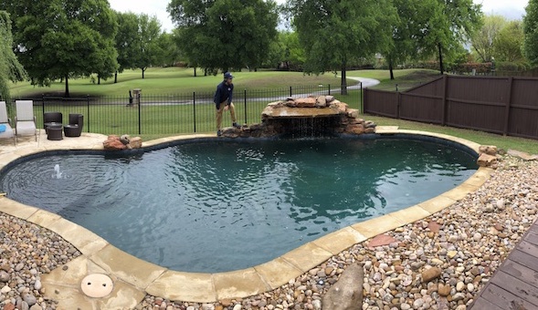 Pool technician cleaning a pool in a backyard of a home for sale