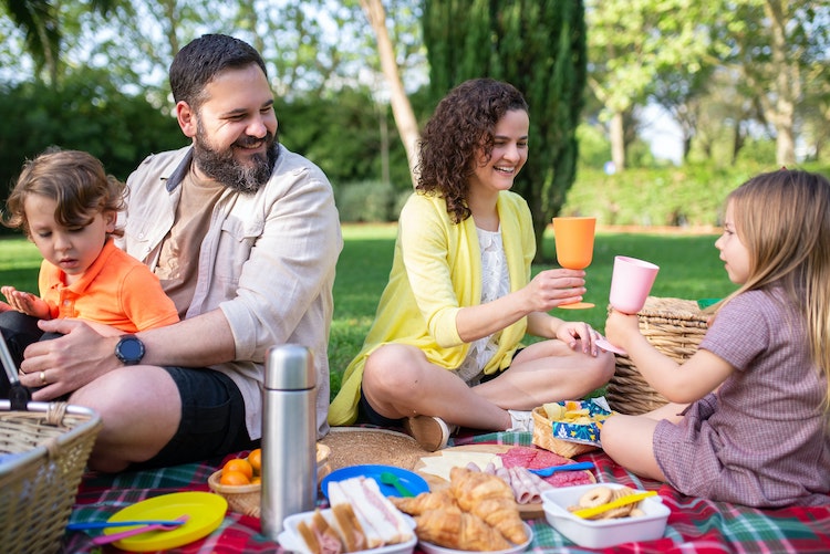Family sitting on picnic blanket in park laughing