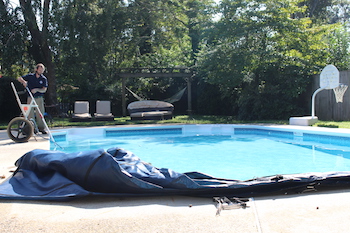 Pool technician taking off a pool cover for a pool opening service