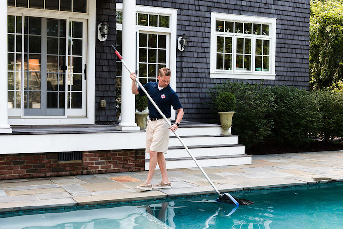 Man cleaning pool with skimmer net