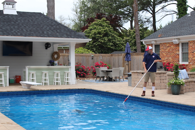 Pool technician skimming a pool