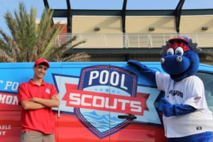 Pool Scouts technician and Blue Wahoos mascot standing in front of a Pool Scouts van outside of a building with a palm tree