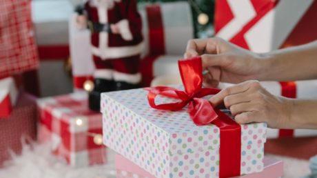 Person opening a gift wrapped in Christmas wrapping paper