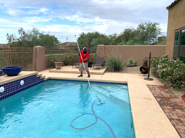 Pool technician using pool net to get debris from pool