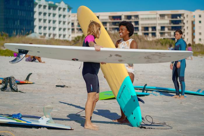 Friends laughing as they're about to go out and surf in Cocoa