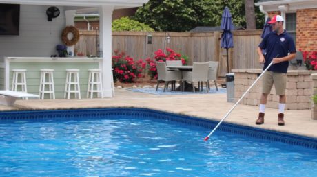Pool technician sweeping pool as part of pool service