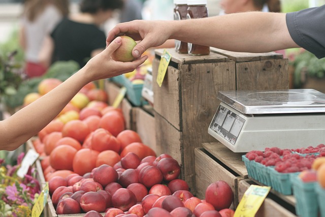 Person at a local farmers market picking up an apple to buy