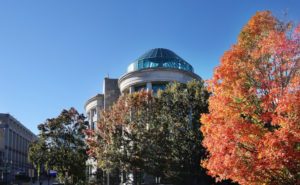 North Carolina Museum of Natural Sciences with a tree with orange fall colored leaves in front