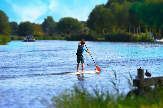 Man paddleboarding on a lake with trees in the background