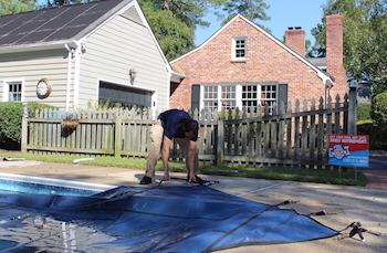 Pool technician putting a pool cover on swimming pool for winter