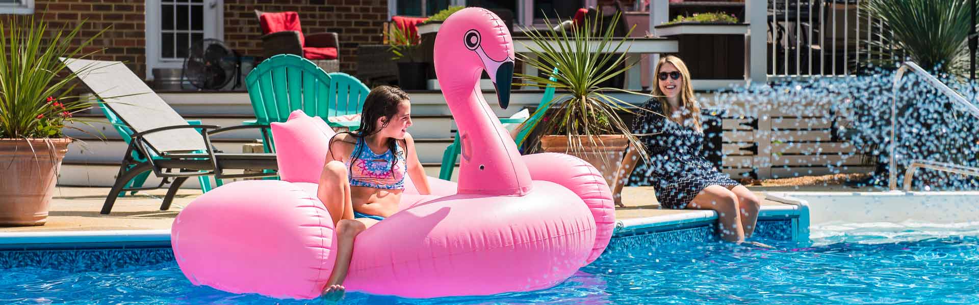 Little girl on flamingo float by a clean swimming pool