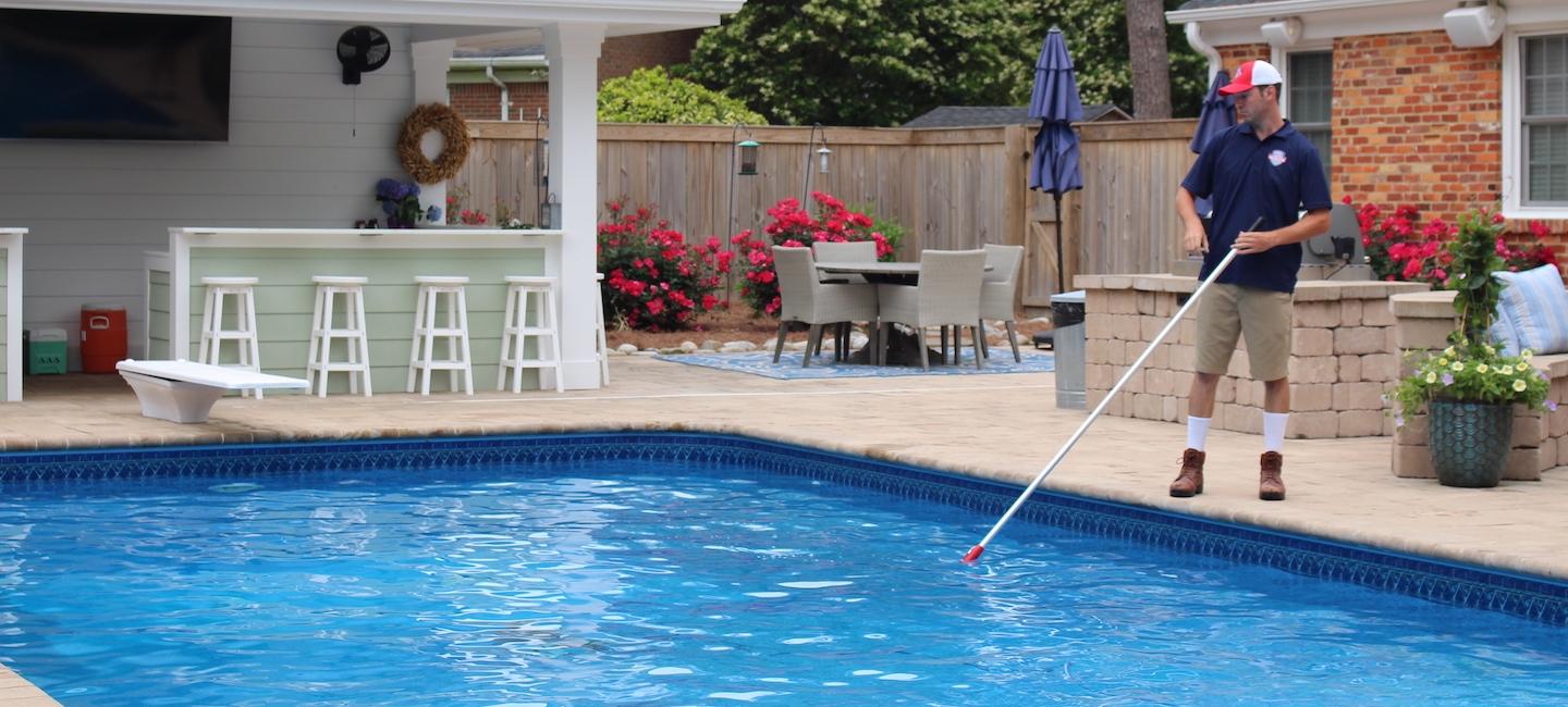 Pool technician sweeping pool as part of pool service