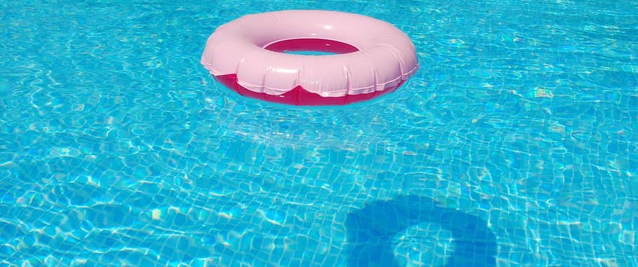 Pink swimming pool float in clear pool on sunny day